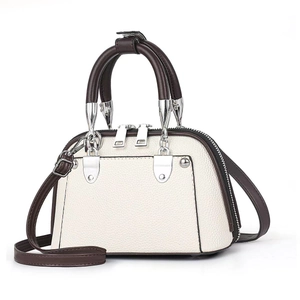 Close-up of litchi texture cream handbag with brown handles and silver zipper details