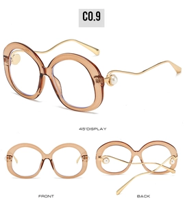 Detail of oval tea amber glasses frame with wave golden metal temples and pearl accent