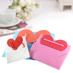 Three elegant paper gift bags with red heart-shaped handles in white pink and blue colors