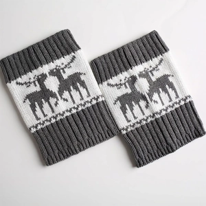 Close-up of dark grey knit leg warmers with white reindeer pattern and ribbed cuffs