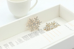 Macro detail of sparkling crystal snowflake brooches on white gift packaging