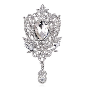 Macro detail of silver vintage brooch featuring pomegranate design and crystal teardrop
