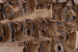 Macro shot of rustic bark-on wood alphabet letters on burlap texture for DIY decor