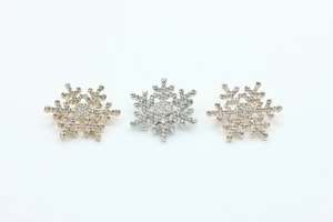 Detailed view of rhinestone snowflake brooches in gold, silver and rose gold set