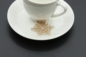 Detailed back view of gold snowflake brooch featuring a secure safety pin closure