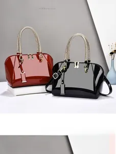 Detail of glossy patent leather shell bag with woven metallic handle and gold lock