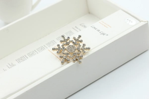 Detail of a sparkling snowflake brooch with rhinestones in a white gift box