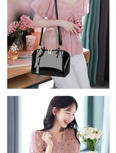 Detail of black patent leather shell bag featuring golden woven handles and dual zip