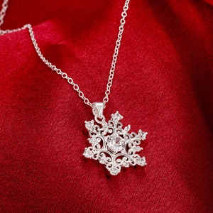 Snowflake pendant necklace with sparkling zircons on red silk background
