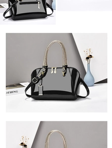 Detail of black patent leather Boston bag featuring gold braided handles and mirror finish