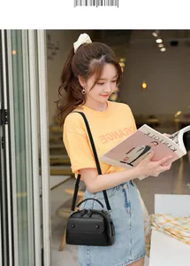 Lifestyle view of black pebbled leather tote bag with dual zippers and round handle