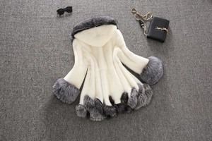 Detail of white and grey faux fur coat featuring a plush hood and contrast trim texture