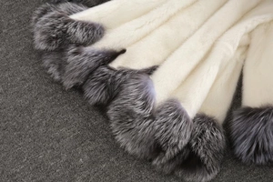 Detailed close-up of cream faux fur coat with silver-grey tips and decorative fur balls