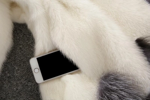 Detail shot of deep pocket on white and grey faux fur coat with a phone for scale
