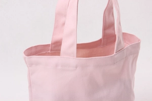 Close-up of pink canvas tote bag showing top handle and fine fabric texture detail