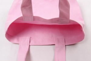 Detailed close-up of pink canvas bag handles and reinforced stitching for lunch bag