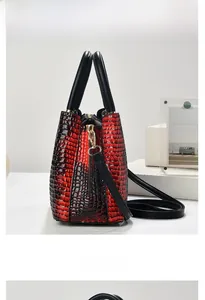 Macro view of gradient red crocodile pattern leather handbag with gold metal hardware