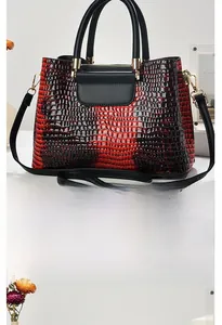 Macro view of red and black gradient crocodile embossed texture on a glossy tote bag