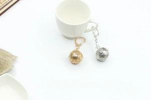 Close-up of gold and silver hollow metal ball pendants on a minimalist white background