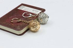 Detail of hollow sphere metal keychains in gold and silver finish on vintage book