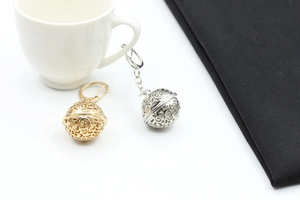 Detailed close-up of hollow metal pendant bells in gold and silver finish with floral pattern