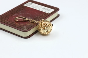 Detailed view of hollow sphere keychain with intricate filigree texture and lobster clasp