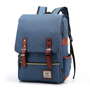 Close-up of blue canvas backpack featuring brown leather straps and metal magnetic buckles