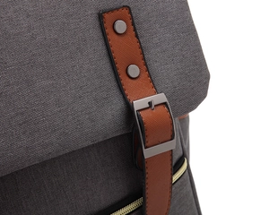 Close-up of grey canvas backpack featuring brown PU leather straps and metal buckles