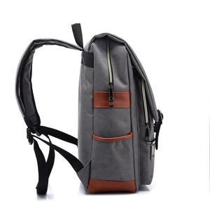 Side view of retro canvas backpack in gray with brown leather trim and adjustable straps