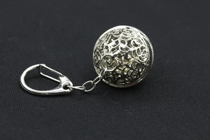 Detailed macro view of the silver hollow-out spherical metal keychain on dark fabric