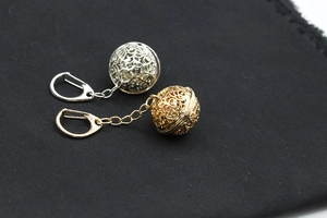 Close-up of hollow alloy ball keychains in gold and silver finish on black fabric