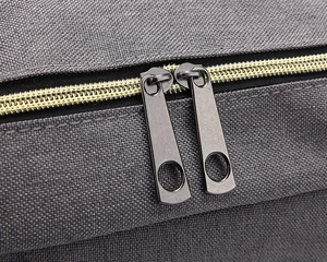 Close-up of grey canvas fabric texture with dual black metal zippers and yellow teeth