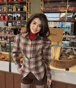Detail of brown plaid long-sleeved shirt featuring side slits and asymmetric hem design