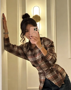 Close-up of brown plaid long sleeve shirt with waist tie and textured cotton-linen fabric