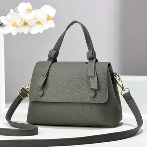 Detail of dark grey lychee pattern leather handbag with elegant gold metal hardware