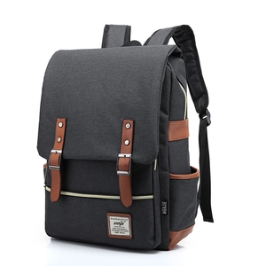 Detail of dark grey canvas backpack with brown leather straps and metal buckle closure