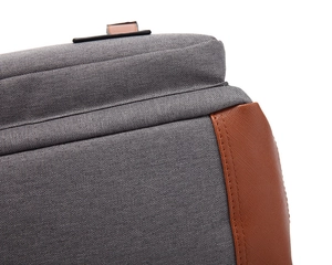 Detail showing the gray canvas fabric and brown leather stitching on the backpack corner
