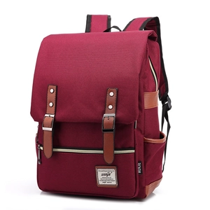 Detail of red canvas backpack featuring brown leather straps and vintage buckle design