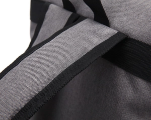 Macro view of gray canvas backpack straps with reinforced black webbing stitching