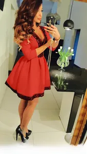Dettaglio dell'abito rosso con scollo a V, pizzo nero e gonna a pieghe svasata