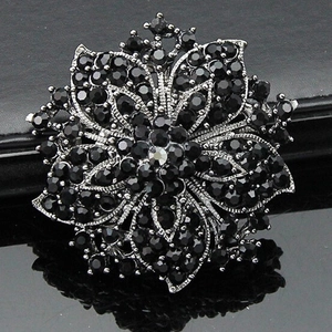 Close-up of elegant silver flower brooch with black rhinestones and layered petals design