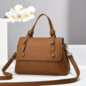 Detailed macro shot of brown lychee grain leather handbag with gold metal hardware