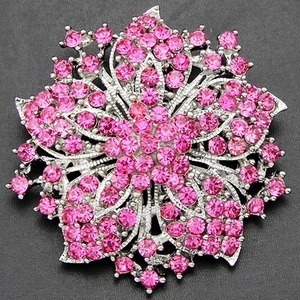 Macro detail of a silver floral brooch encrusted with vibrant pink rhinestones and crystals