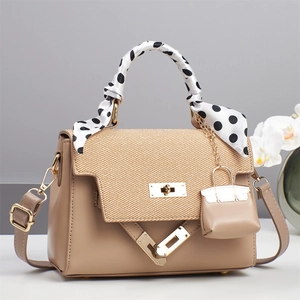 Detail of khaki leather handbag with straw texture flap and polka dot scarf handle