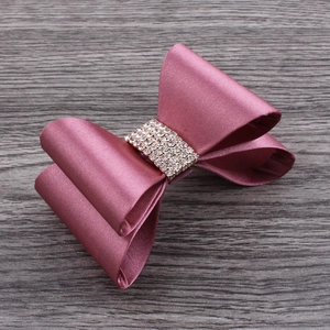 Detail of dusty pink satin bow hair clip with central sparkling crystal rhinestone