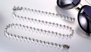 Close-up of polished stainless steel ball chain necklace with secure clasp on a grey surface