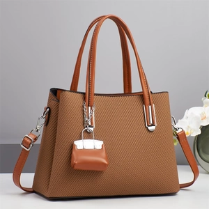 Detail van een bruine geweven shopper met een mini-tashanger en zilverkleurig beslag