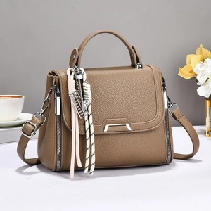 Brown litchi grain leather crossbody handbag with woven pendant and adjustable strap