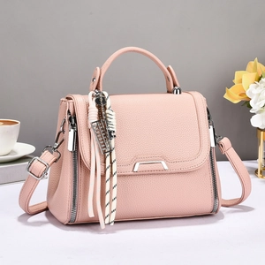 Close-up of pink litchi grain leather bag with silver metal bar and tassel charm