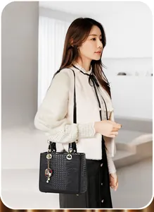 Detailed view of black crocodile pattern handbag with golden ring handle and charm